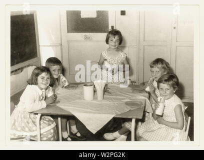 Photo originale du milieu du siècle des années 1960 d'enfants heureux de l'école primaire de boire du lait gratuit à l'école à partir d'une bouteille , peut-être Leicestershire, Royaume-Uni Banque D'Images