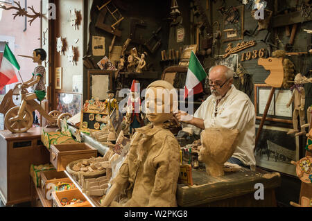 Menuisier italien travaillant sur Pinocchio jouets en bois dans son atelier/magasin, ouvert au public Banque D'Images