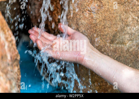 Jeune homme mains libre de natation en Japonais par spa piscine en pierre bleue et l'eau colorée en cascade dans le japon onsen Banque D'Images