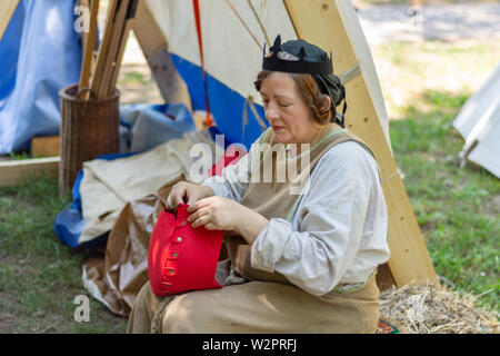 Nis, Serbie - 15 juin. 2019 femme médiévale en costumes traditionnels devant une tente une couture à red hat le chevalier festival. Les anciens métiers médiévaux Banque D'Images
