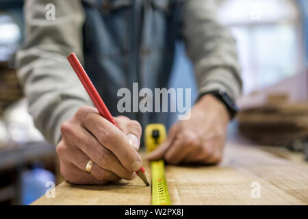 Carpenter measuring et traçage ligne avec une règle et crayon sur bois en bois. Banque D'Images