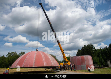 Benneckenstein, Allemagne. 10 juillet, 2019. Une grue soulève le toit d'un ancien dôme radar sur le terrain de l'Ostdeutsche Fahrzeug- und Technikmuseum afin de le soulever sur les murs de l'établissement. Le dôme radar se tenait sur le Brocken jusqu'au début des années 90 et à l'abri des installations techniques militaires sensibles. Le 13 juillet 2019 et 14 juillet 2019 le 4e jours de la technologie auront lieu au Musée de la technologie. Puis le dôme sera visible. Credit : Klaus-Dietmar Gabbert/dpa-Zentralbild/ZB/dpa/Alamy Live News Banque D'Images