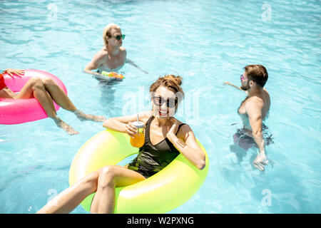 Une jeune femme sur l'anneau gonflable, s'amusant avec des amis dans la piscine de l'eau pendant l'été Banque D'Images