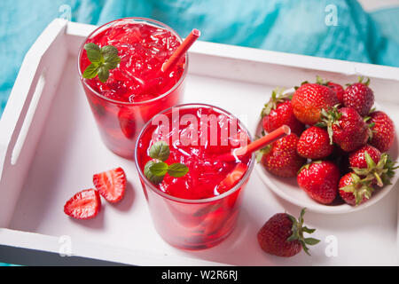 Lunettes avec fraises fraîches maison thé glacé sucré ou un cocktail, limonade avec les feuilles de menthe et la plaque avec la fraise. Boisson fraîche. L'été Banque D'Images