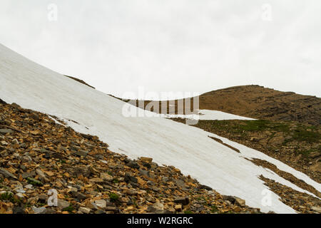 Les randonneurs à l'horizon près de la partie supérieure du champ de neige sur le côté sud de Siyeh Pass, Glacier National Park, Montana, USA. Banque D'Images