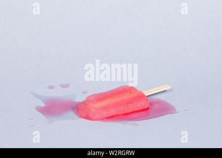 Fusion dans un Popsicle rose fond bleu Banque D'Images