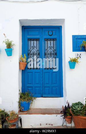 Porte peinte bleu typique avec des plantes en pot sur un mur blanc à Frigiliana, Province de Malaga, Espagne. Banque D'Images