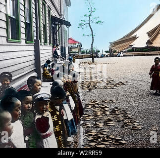 [ 1900 - Japon ] Les enfants de l'école élémentaire Japonais Japonais - les enfants de l'école primaire en face d'un bâtiment scolaire, ca. 1904-1905. Remarquez les alignés de chaussures. 20e siècle vintage lame de verre. Banque D'Images