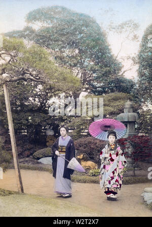 [ 1890 - Japon la femme japonaise avec des parasols ] - deux femmes en kimono holding parasols poser dans un jardin de style japonais. Dans le dos une lanterne de pierre peut être vu. 19e siècle vintage albumen photo. Banque D'Images