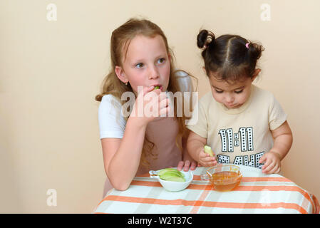 Close up portrait of two funny cute little girl apple manger avec du miel à l'intérieur. Enfants juifs trempant des tranches de pomme dans le miel à Roch Hachana le Jewi Banque D'Images