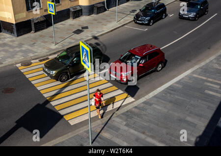 30 mai 2019, Moscou, Russie. La jeune fille en rouge traverse la rue à un passage pour piétons à Moscou. Banque D'Images