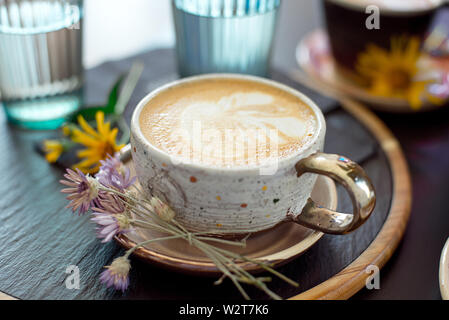 Différents types de café dans une tasse sur une table, deux verres d'eau froide et de fleurs de printemps sur la table, vue du dessus Banque D'Images