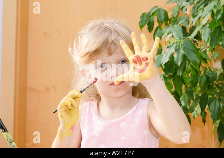 Fille blonde avec des mains peints en jaune Banque D'Images