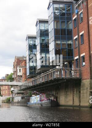 Deux barges moor sous la passerelle piétonne / balcon par le bloc d'appartement à côté de la rivière Aire au centre de Leeds Banque D'Images