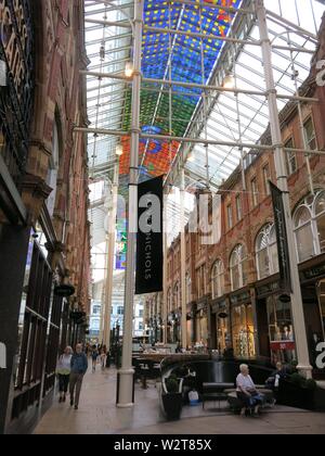 Photo des vitraux colorés, toit des cafés et une bannière pour Harvey Nichols dans le quartier Victoria Quarter Arcade Banque D'Images