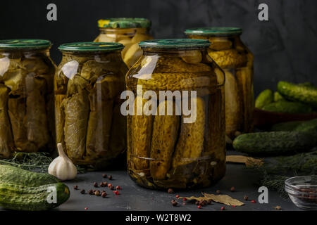 Différents concombres et courgettes, l'ail et feuilles de vigne en pots sur un fond sombre, photo horizontale Banque D'Images