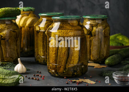 Différents concombres et courgettes, l'ail et feuilles de vigne en pots sur un fond sombre, photo horizontale Banque D'Images