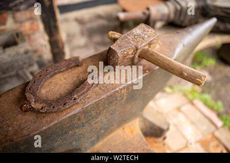 Outils dans un ancien atelier de forgeron. Horseshoe et marteau sur une grande enclume. Place - musée en plein air. Banque D'Images