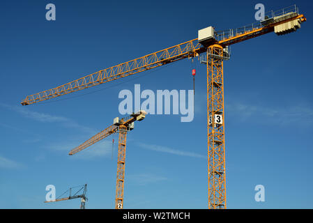 Grues de construction jaune en métal contre un ciel bleu Banque D'Images