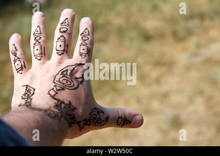 Un scorpion mehendi arabe dessin sur une mans main sur un arrière-plan flou de prairies, selective focus Banque D'Images