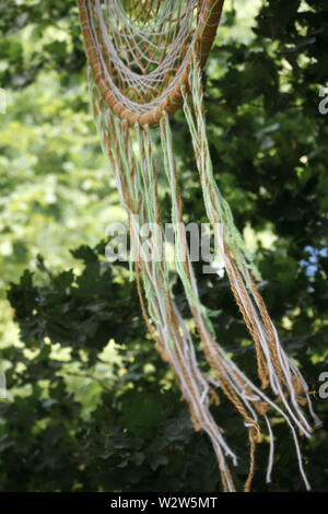 Closeup of a multi-couleur tissé main macrame dreamcatcher accroché à une branche dans le parc Banque D'Images