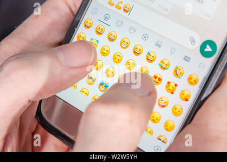 Une personne tapant caractères Emoji dans un chat app Banque D'Images