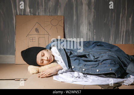 Petite fille sans-abri dormir sur le plancher près de wall Banque D'Images