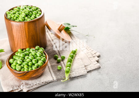 Bol et pot avec de délicieux petits pois frais sur fond gris Banque D'Images