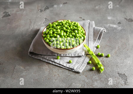 Bol avec de délicieux petits pois frais sur grunge background Banque D'Images