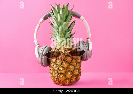 Drôle avec ananas et lunettes écouteurs sur un fond de couleur Banque D'Images