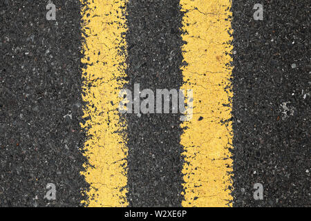 Route asphaltée avec ligne de démarcation jaune double, vue du dessus. Texture de fond Transport Banque D'Images