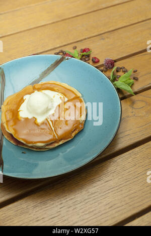 Crêpes à la crème glacée en plaque bleue sur la table en bois Banque D'Images