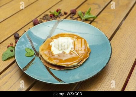 Crêpes à la crème glacée en plaque bleue sur la table en bois Banque D'Images