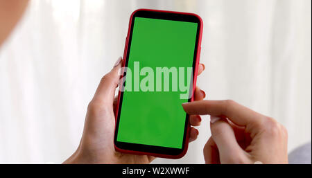 La main féminine avec un smartphone écran vert Banque D'Images