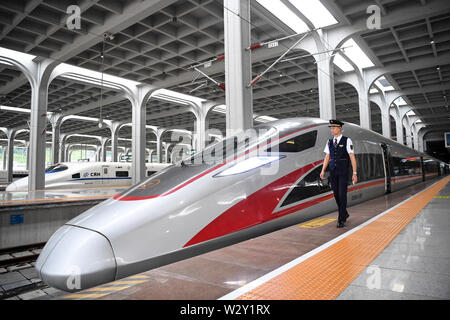 (190711) -- CHONGQING, 11 juillet 2019 (Xinhua) -- un membre du personnel de chemin de fer passe devant le train G319 à la gare de l'ouest de Chongqing dans le sud-ouest de la Chine, Chongqing, le 11 juillet 2019. Le bullet train G319 a quitté la gare de l'ouest de Chongqing à 8 h 20 et arrivera à Hong Kong West Kowloon Station autour de 7,5 heures plus tard. Un siège de seconde classe pour les 7,5 heures de voiture coûte 660 yuans (environ 96 dollars américains). (Xinhua/Tang Yi) Banque D'Images