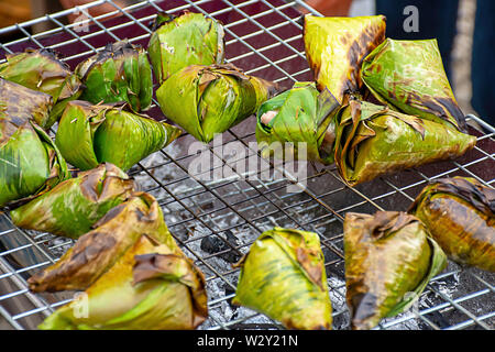 Riz gluant enveloppé dans des feuilles de bananier, rôti sur le grill est un aliment populaire en Thaïlande. Banque D'Images