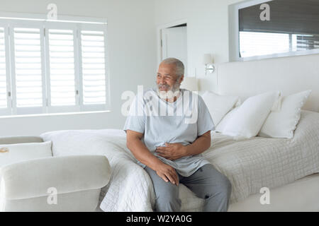 Homme assis sur le lit en souriant Banque D'Images