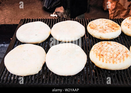 Ronde, savoureuse, faits à la main lush fait des tortillas de farine de blé sont cuits sur le grill grille sur des charbons ardents. Le pain est rôti sur un barbecue en plein air pour c Banque D'Images