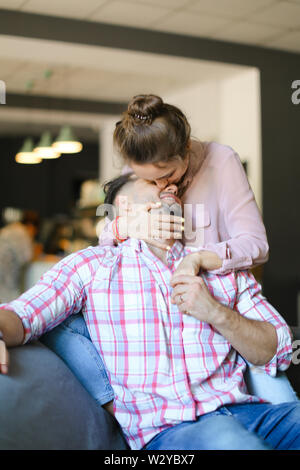Jeune femme caucasienne embrasser et s'étreindre mari à la maison. Concept de passer du temps ensemble, la relation et l'amour. Banque D'Images