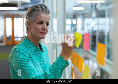La femme écrit sur un post-it in office Banque D'Images