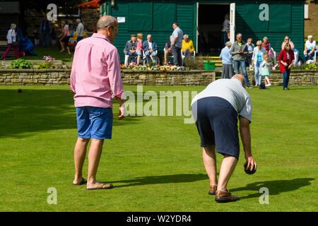2 hommes jouant bols sur cible à Bowling Green fun event (l'homme à propos de bol, regarder les gens) - Burley-In-Wharfedale, West Yorkshire, England, UK Banque D'Images