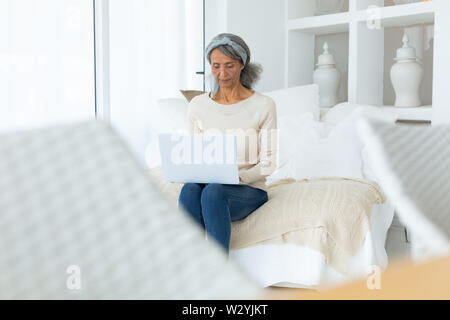 Femme assise lors de l'utilisation d'un ordinateur portable blanc. Banque D'Images