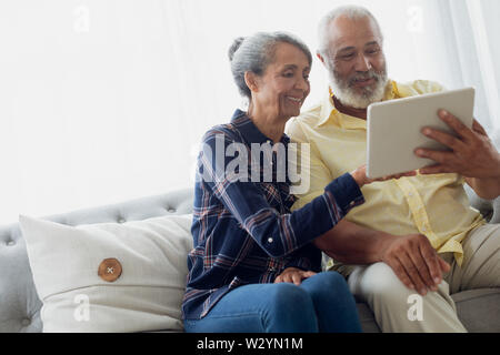 Couple sitting on couch pendant l'utilisation d'une tablette Banque D'Images