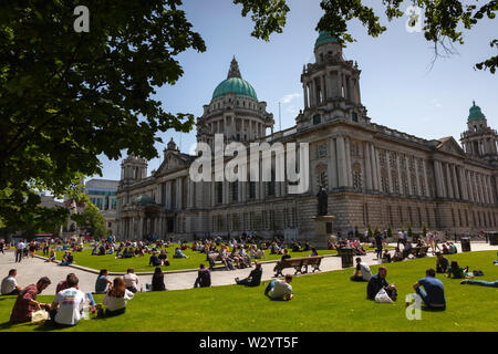 L'Irlande du Nord, Belfast, les touristes et les employés de bureau, de vous détendre sur les pelouses de l'hôtel de ville pendant l'heure du déjeuner. Banque D'Images