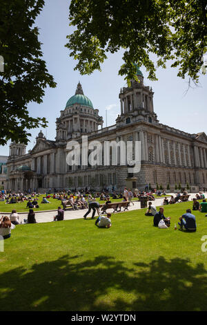 L'Irlande du Nord, Belfast, les touristes et les employés de bureau, de vous détendre sur les pelouses de l'hôtel de ville pendant l'heure du déjeuner. Banque D'Images