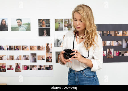 Femme designer graphique Visualisation des photos sur l'appareil photo numérique in office Banque D'Images