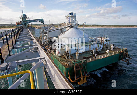 Exploitation minière, gestion et transport des sables bitumineux en titane. Opérations portuaires avec chargement de barges et travaux de jetée marine avant le transport des produits vers l'OGV. Banque D'Images