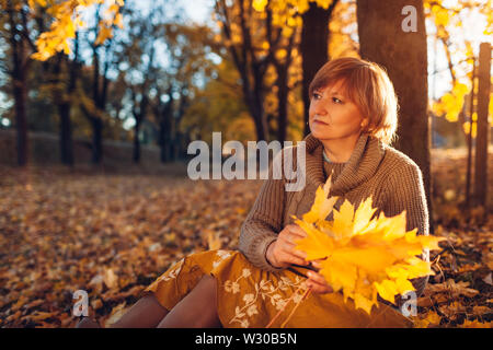 Middle-aged woman holding bouquet de feuilles d'érable. Profiter de dame nature et détente d'automne Banque D'Images