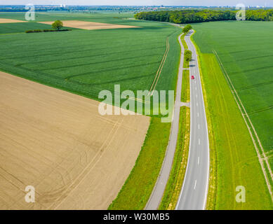 Photographie aérienne avec la caméra drone d'un petit chemin de campagne asphaltée menant à travers champs et prairies. Banque D'Images