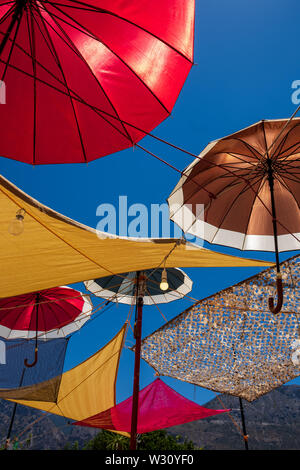 Parasols colorés sur fond de ciel bleu couvrant taverna terrasse dans village de Vasiliki, Crète, Grèce Banque D'Images